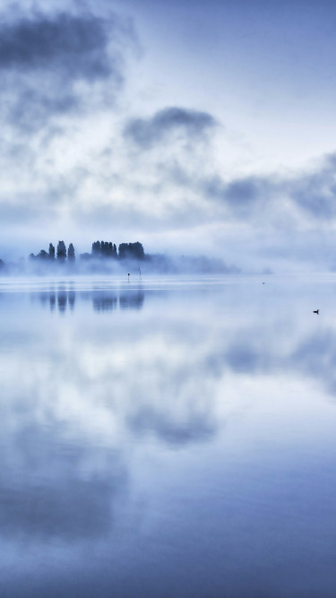 Odbicia chmur na jeziorze w mglisty poranek