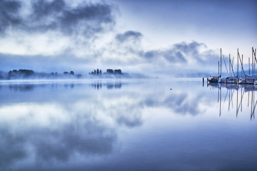 Tapeta Odbicia chmur na jeziorze w mglisty poranek